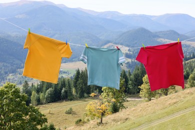 Photo of Washing line with clean laundry and clothespins in mountains