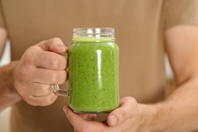 Man holding mason jar with delicious smoothie, closeup