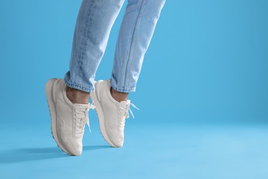 Photo of Man wearing stylish sneakers on light blue background, closeup. Space for text