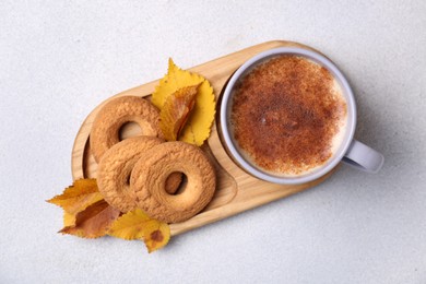 Photo of Cup of hot drink, cookies and autumn leaves on light grey textured table, top view