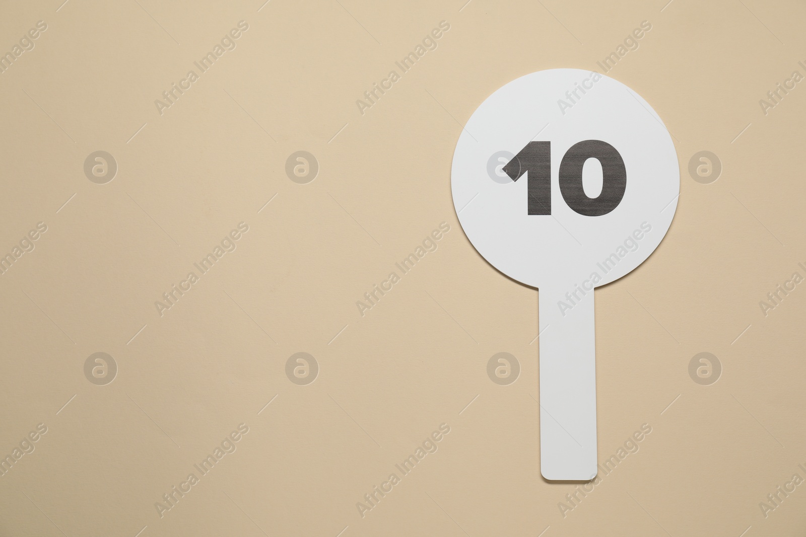 Photo of Auction paddle with number 10 on beige background, top view. Space for text