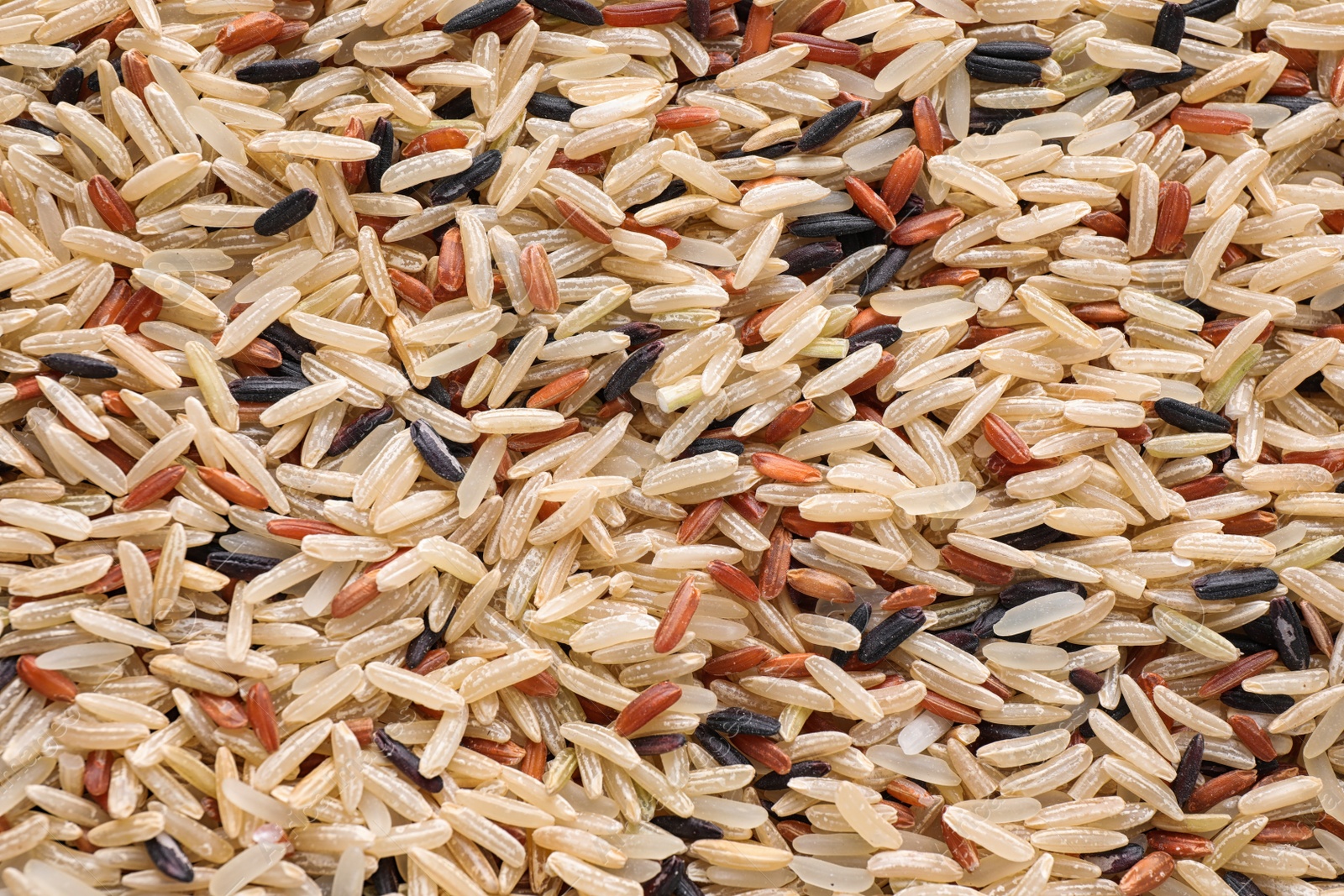 Photo of Mix of different brown rice as background, top view