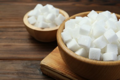 White sugar cubes on wooden table, closeup