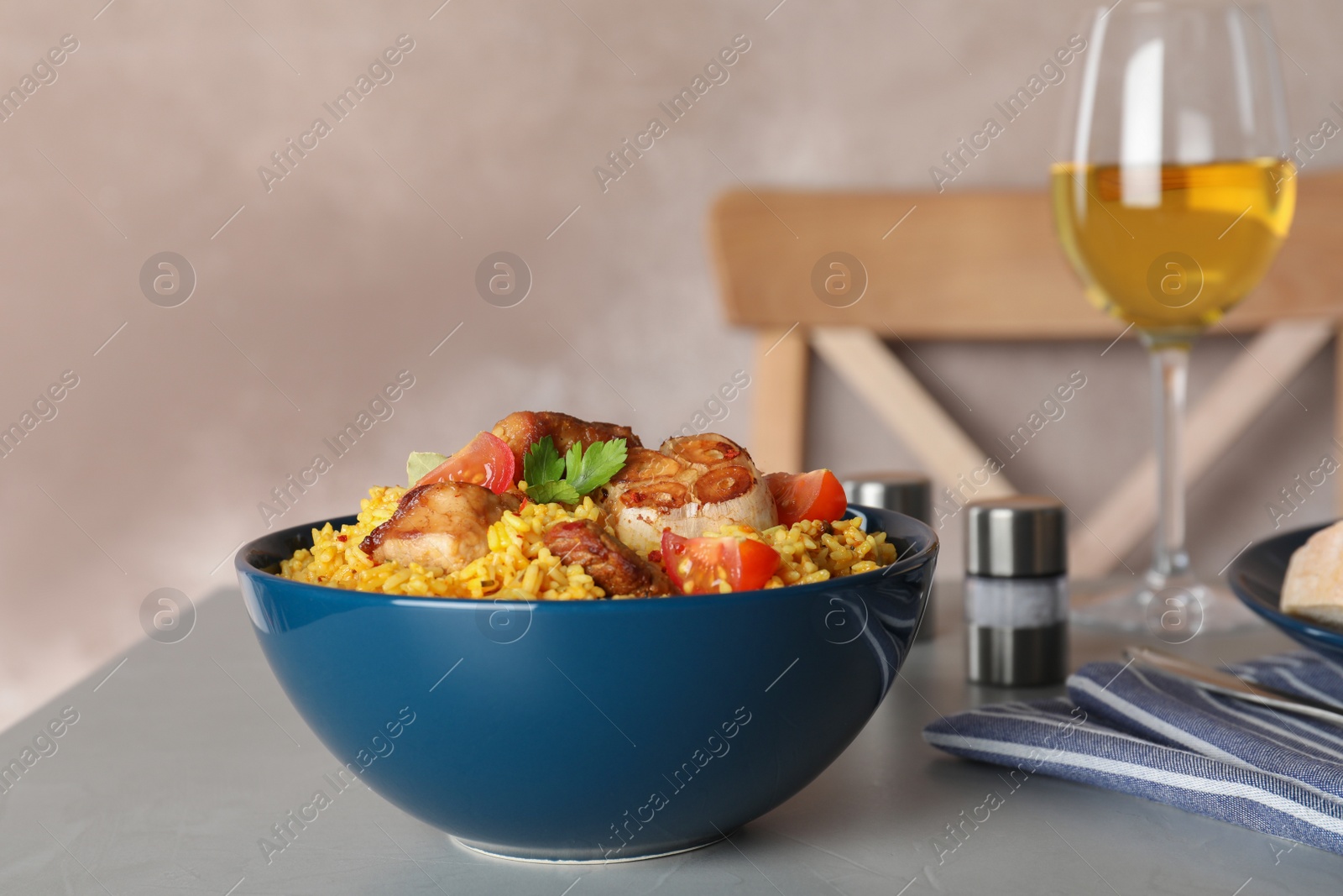 Photo of Bowl with delicious rice pilaf served on table against color background