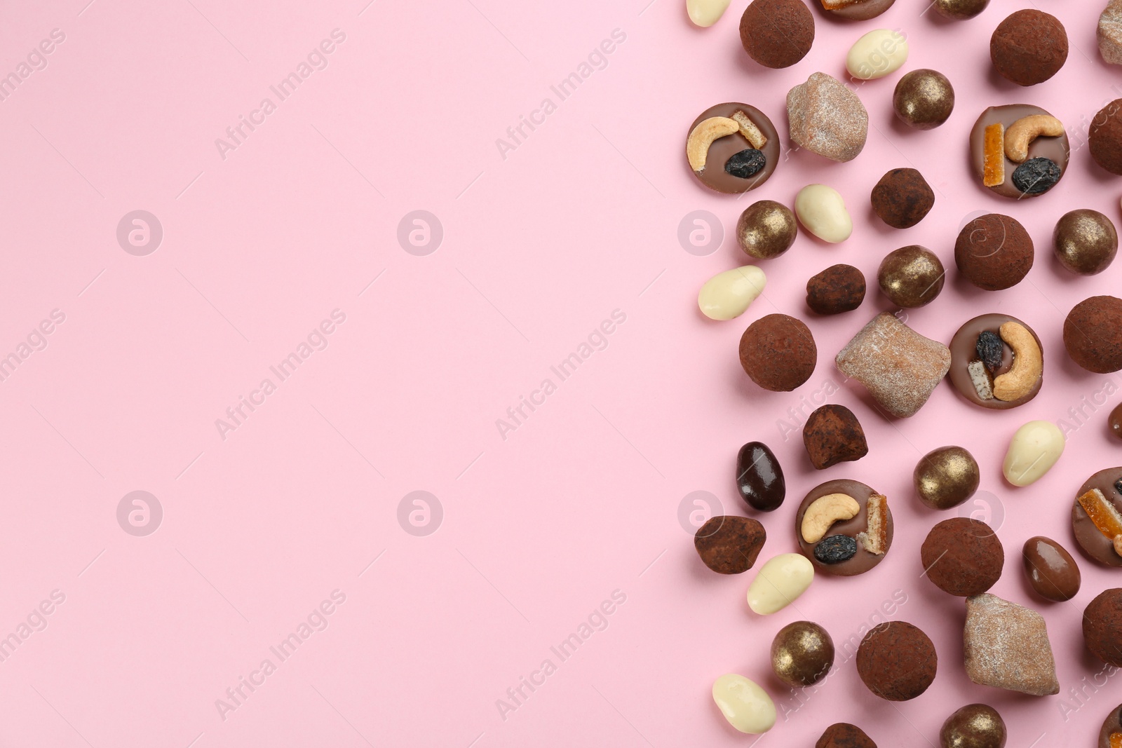 Photo of Different delicious chocolate candies on light pink background, flat lay. Space for text