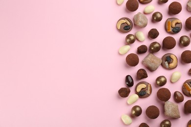 Different delicious chocolate candies on light pink background, flat lay. Space for text