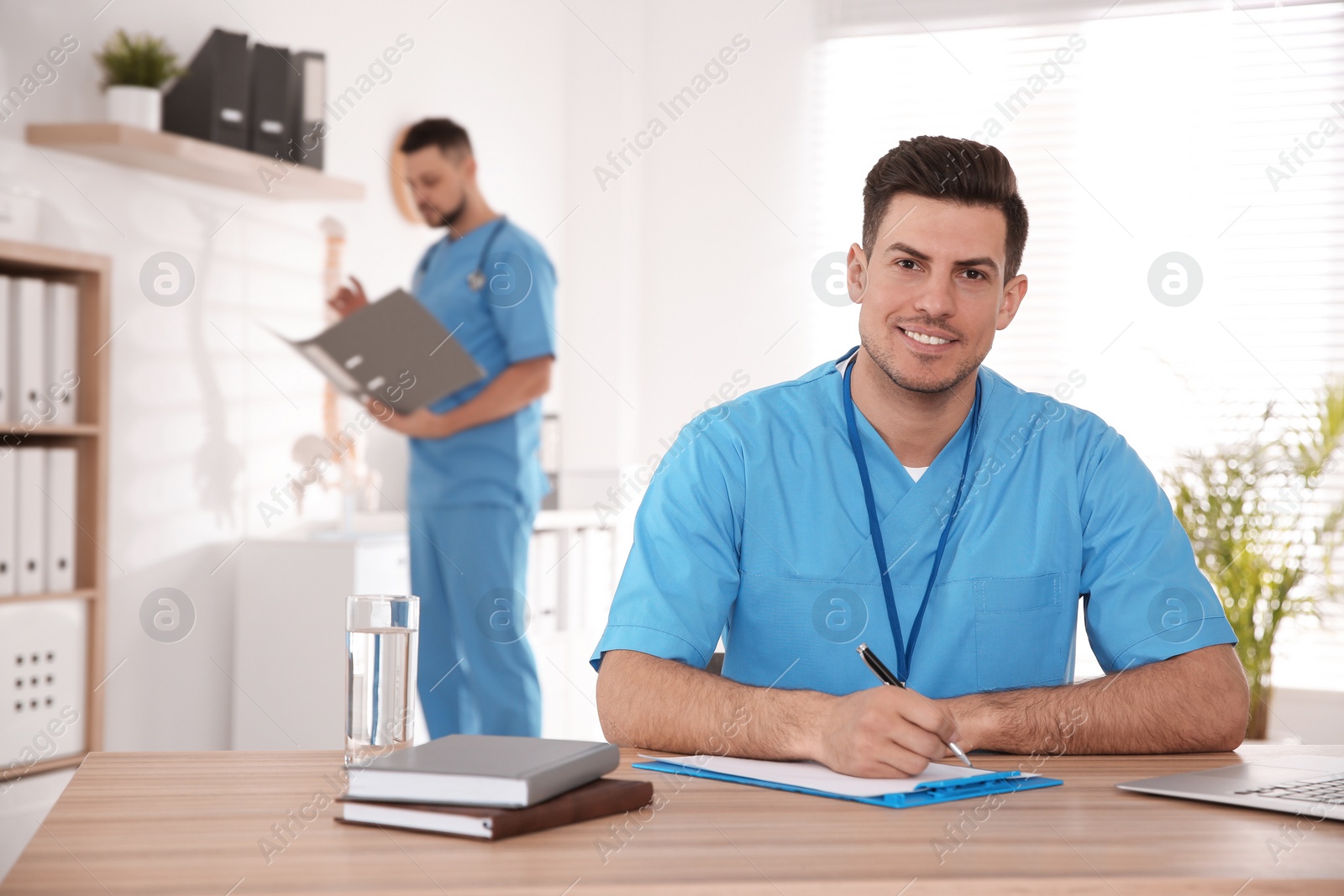 Photo of Portrait of male doctor at table in modern clinic