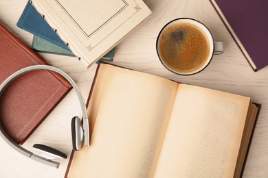 Books, coffee and headphones on white wooden table, flat lay