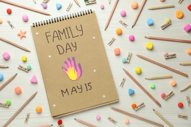 Photo of Happy Family Day. Flat lay composition with notebook and stationery on white wooden table