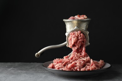 Photo of Manual meat grinder with beef mince on grey table, space for text