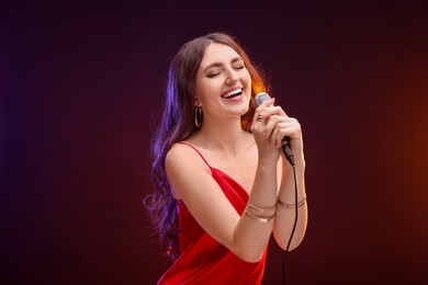 Emotional woman with microphone singing in color lights