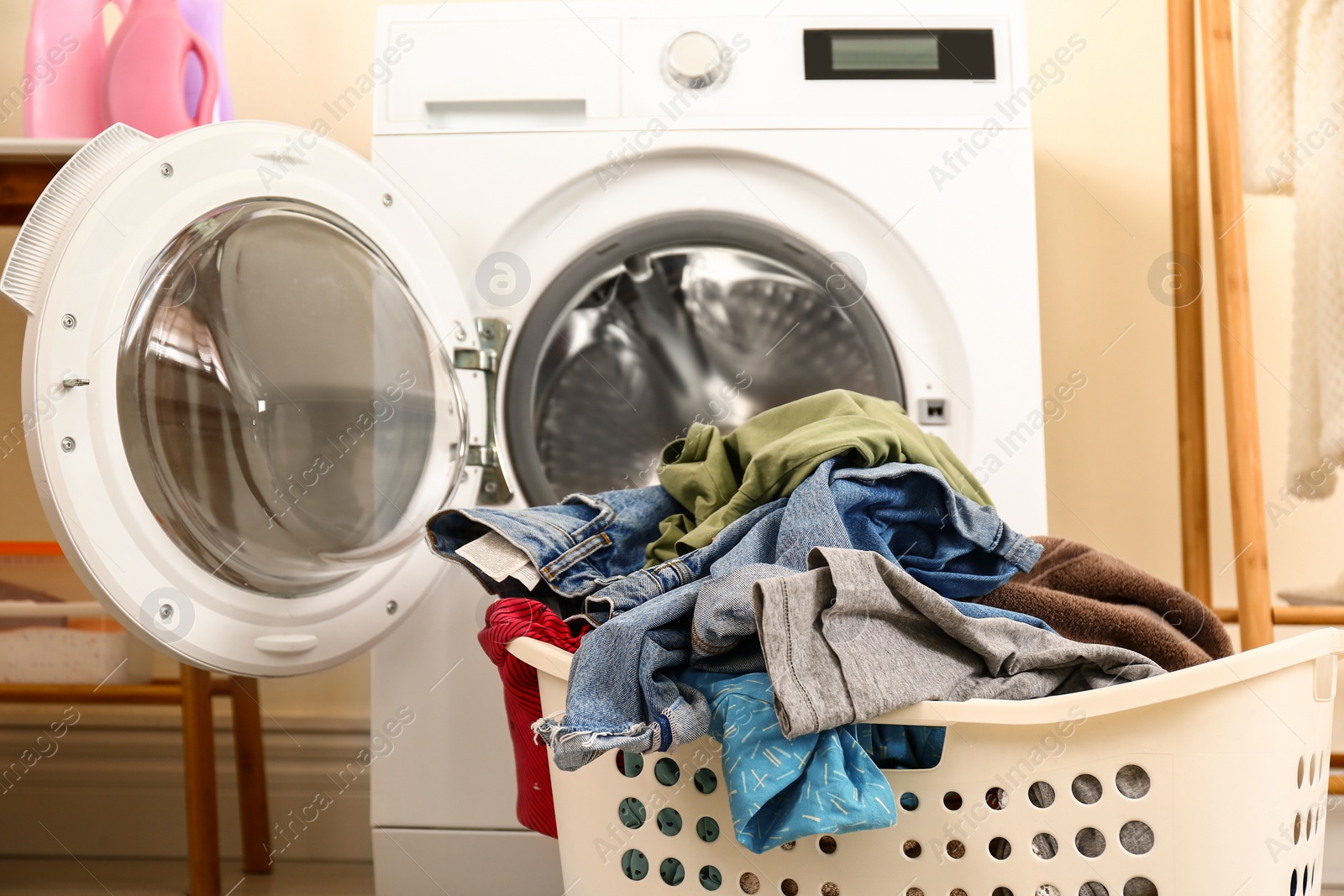 Photo of Basket with dirty laundry near washing machine indoors