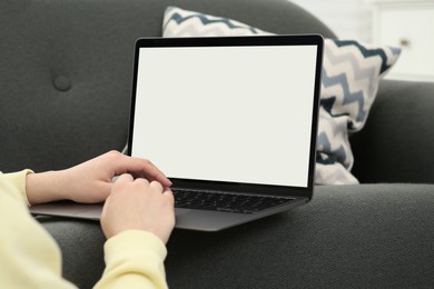 Woman using laptop on couch at home, closeup