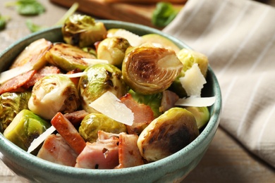 Image of Delicious fried Brussels sprouts with bacon in bowl on table, closeup