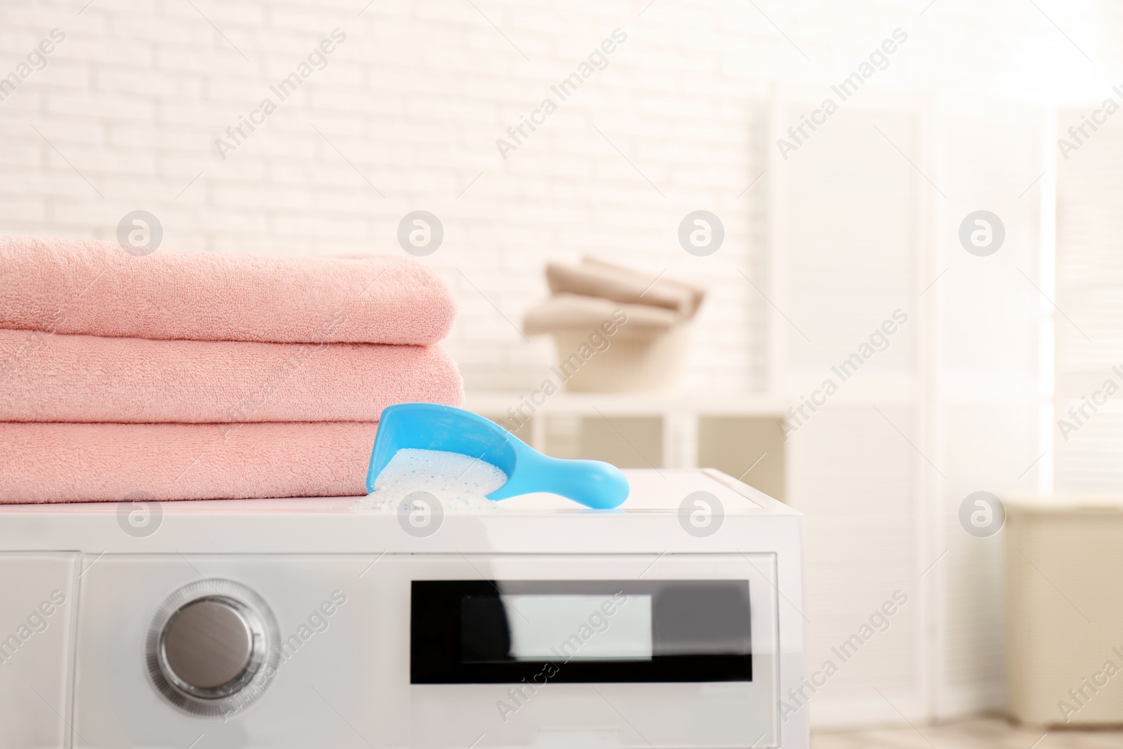 Photo of Scoop of powder and clean towels on washing machine indoors, space for text. Laundry day