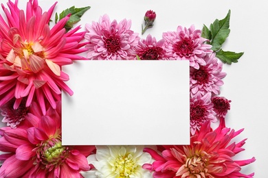 Flat lay composition with beautiful dahlia flowers and blank card on white background