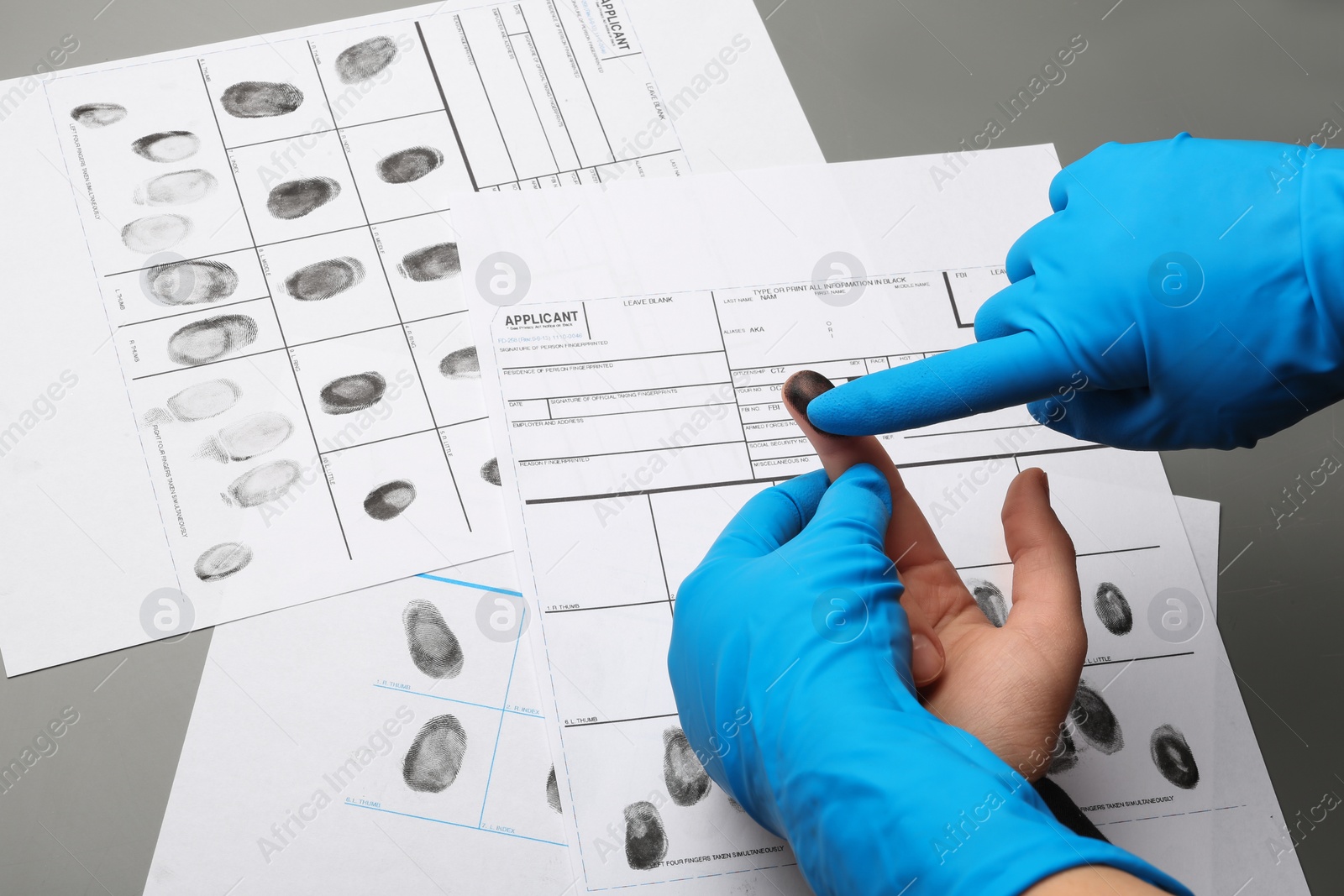 Photo of Investigator taking fingerprints of suspect at table, closeup. Criminal expertise