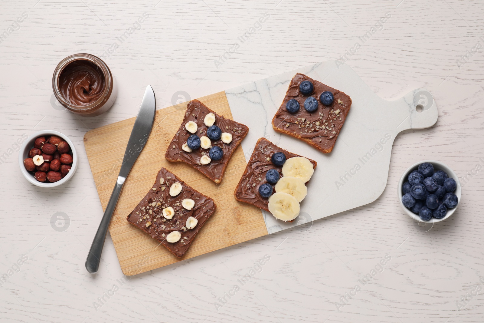 Photo of Different tasty toasts with nut butter and products on white wooden table, flat lay