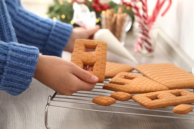 Photo of Woman making gingerbread house at wooden table, closeup