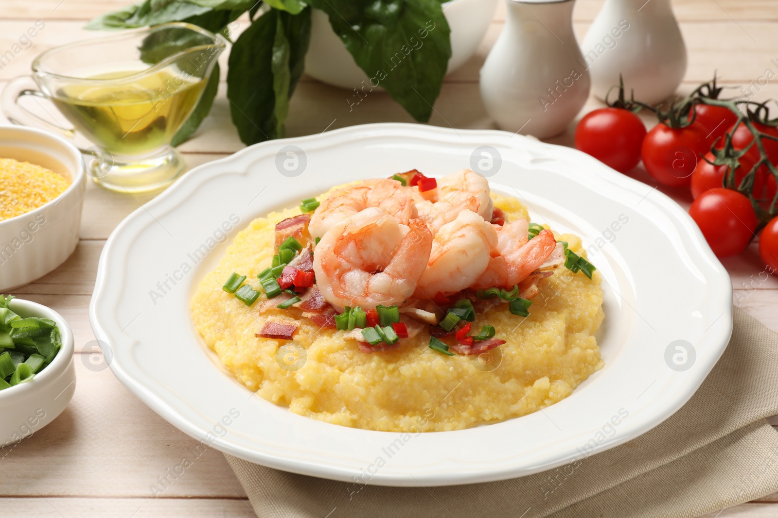 Photo of Plate with fresh tasty shrimps, bacon, grits, green onion and pepper on wooden table, closeup