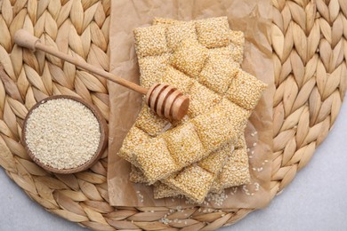 Delicious sweet kozinaki bars, sesame seeds and wooden dipper on light grey table, flat lay