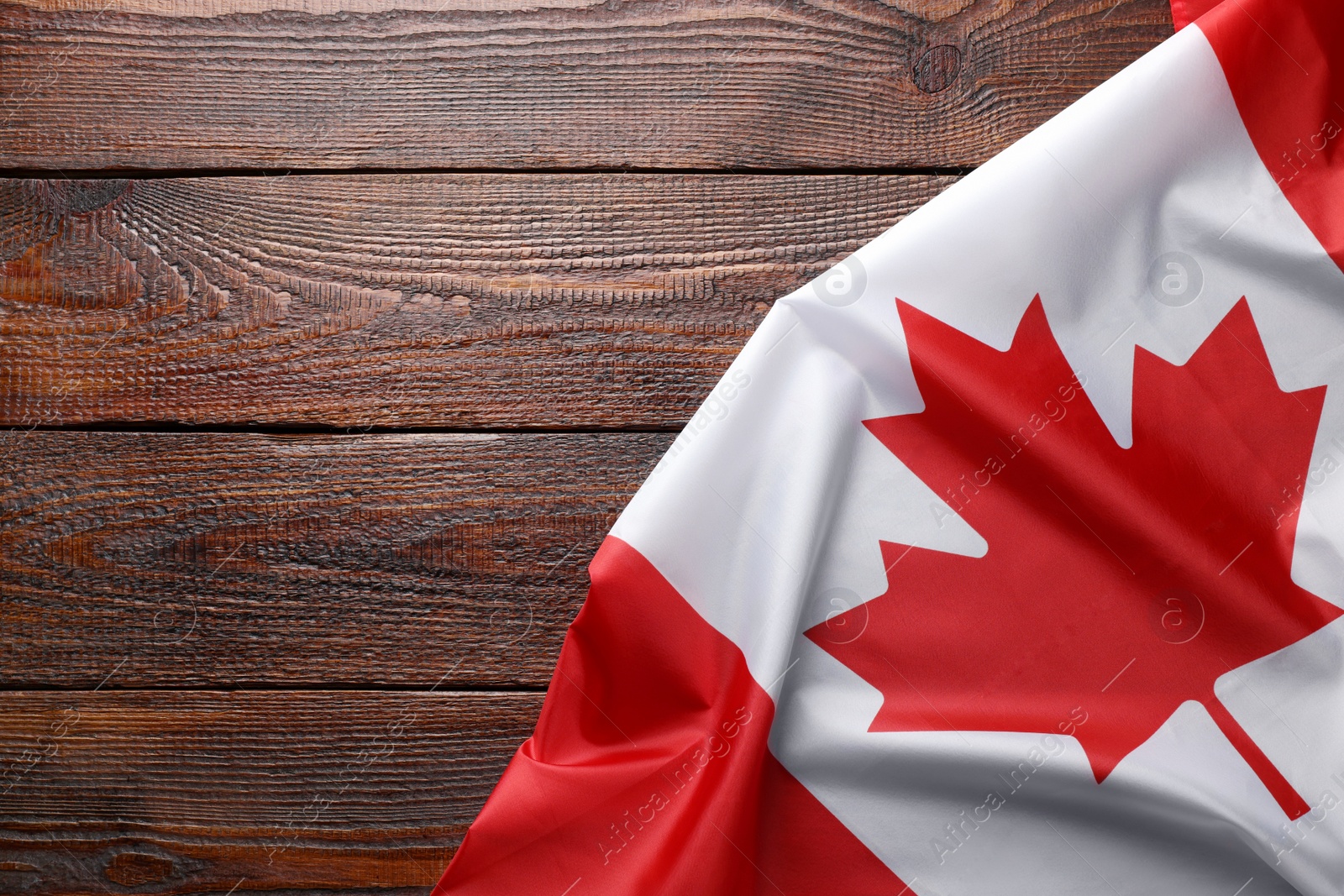 Photo of Flag of Canada on wooden table, top view. Space for text