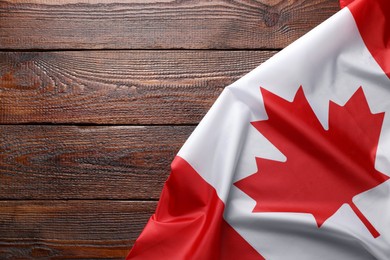 Flag of Canada on wooden table, top view. Space for text