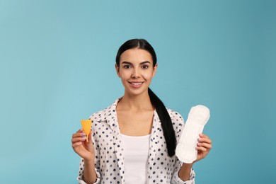 Photo of Young woman with menstrual cup and pad on light blue background