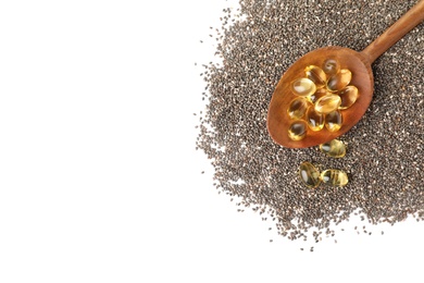 Spoon with chia oil capsules and seeds on white background, top view