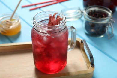 Photo of Mason jar of delicious iced hibiscus tea on light blue wooden table