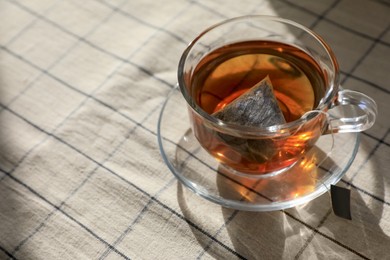 Photo of Tea bag in glass cup on table, closeup. Space for text