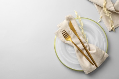 Photo of Stylish setting with cutlery, napkin, dry branch and plate on light grey table, top view. Space for text