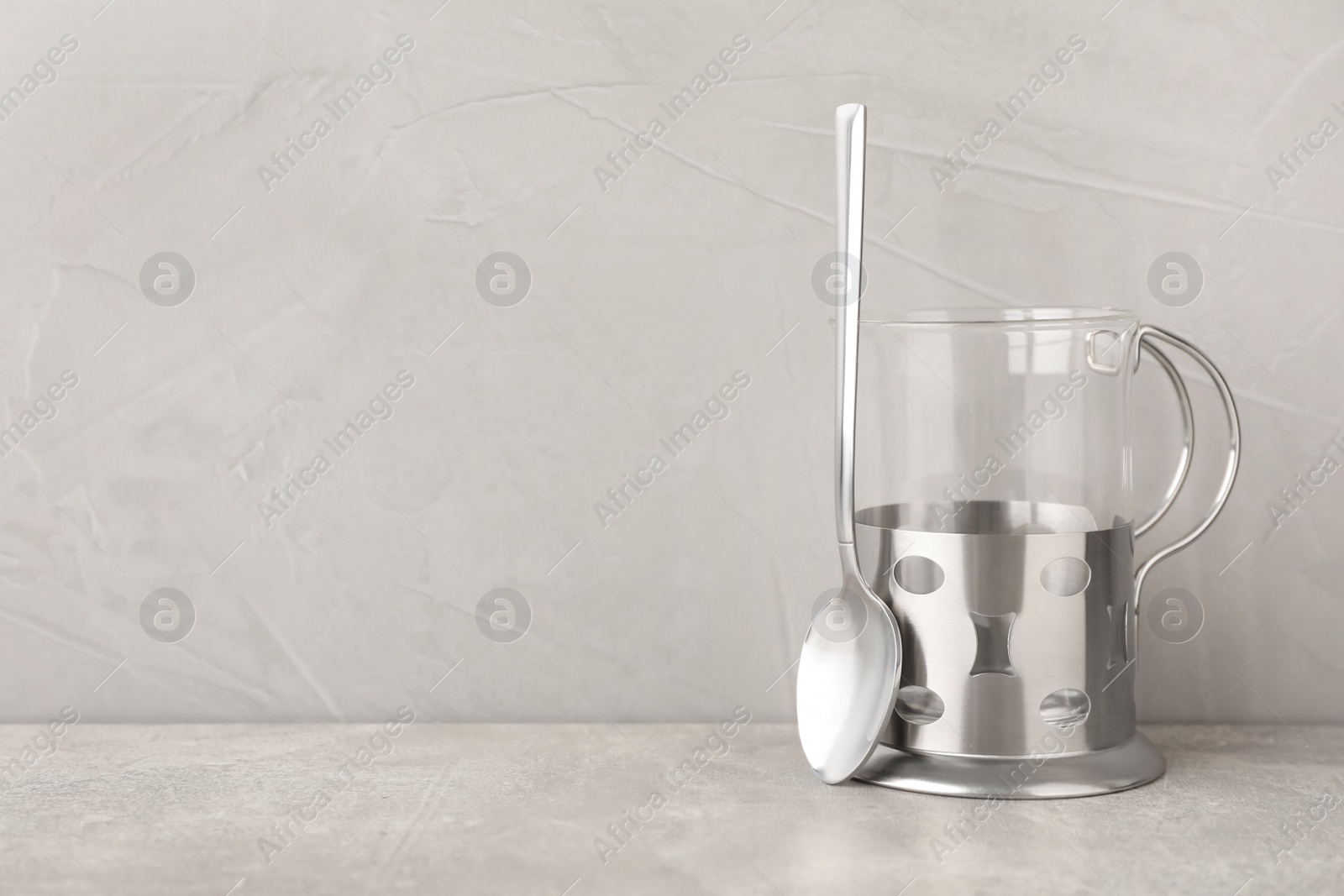 Photo of Traditional tea glass holder and spoon on grey table, space for text