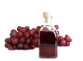 Photo of Glass bottle with wine vinegar and fresh grapes on white background