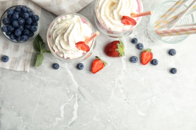 Photo of Tasty milk shakes with fresh berries on grey marble table, flat lay. Space for text