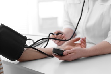 Doctor checking blood pressure of woman in clinic, closeup