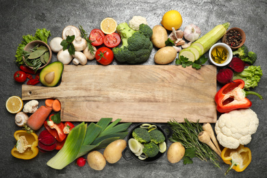 Photo of Fresh products and wooden board with space for text on grey table, flat lay. Healthy cooking