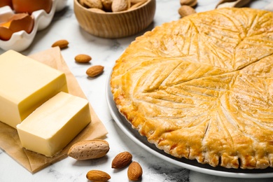 Traditional galette des rois and ingredients on white marble table, closeup