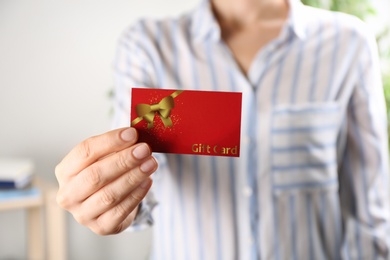 Photo of Woman with gift card on blurred background, closeup