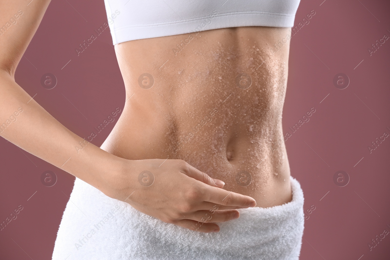 Photo of Young woman applying natural scrub on her belly against color background, closeup