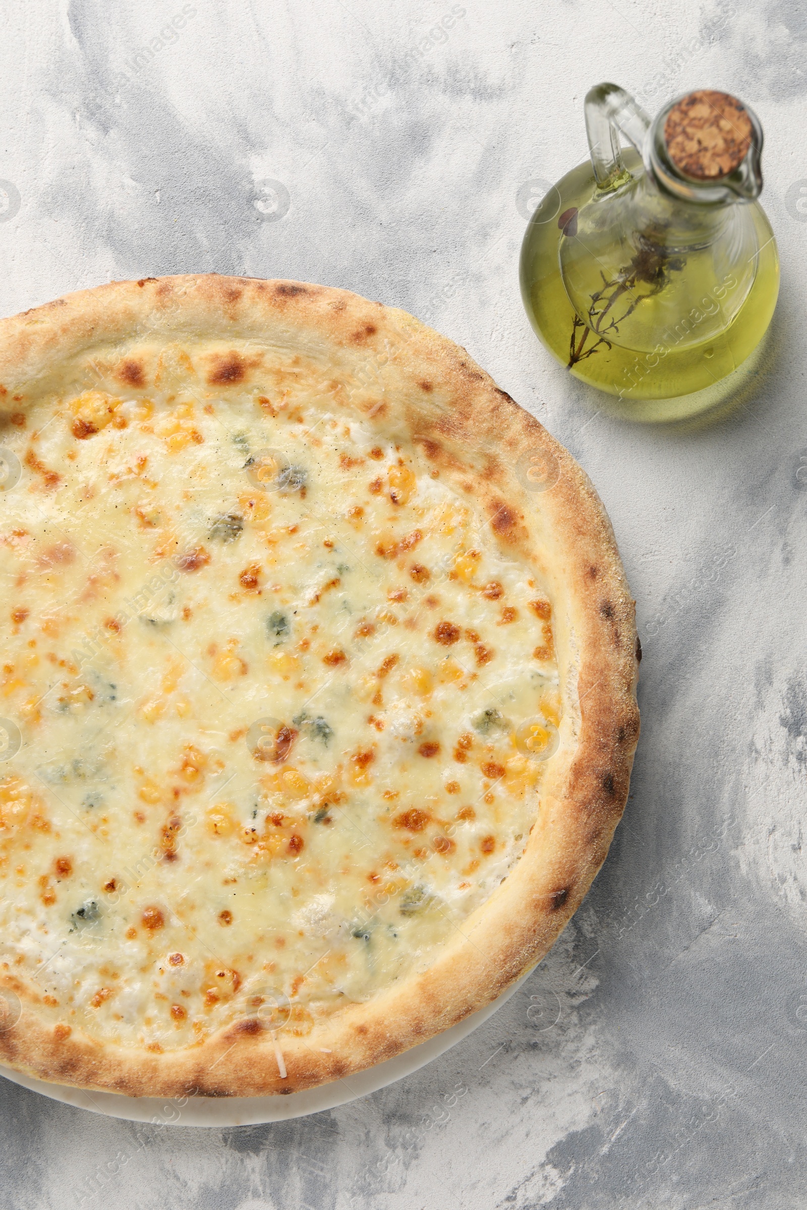 Photo of Delicious cheese pizza and oil on light grey textured table, flat lay