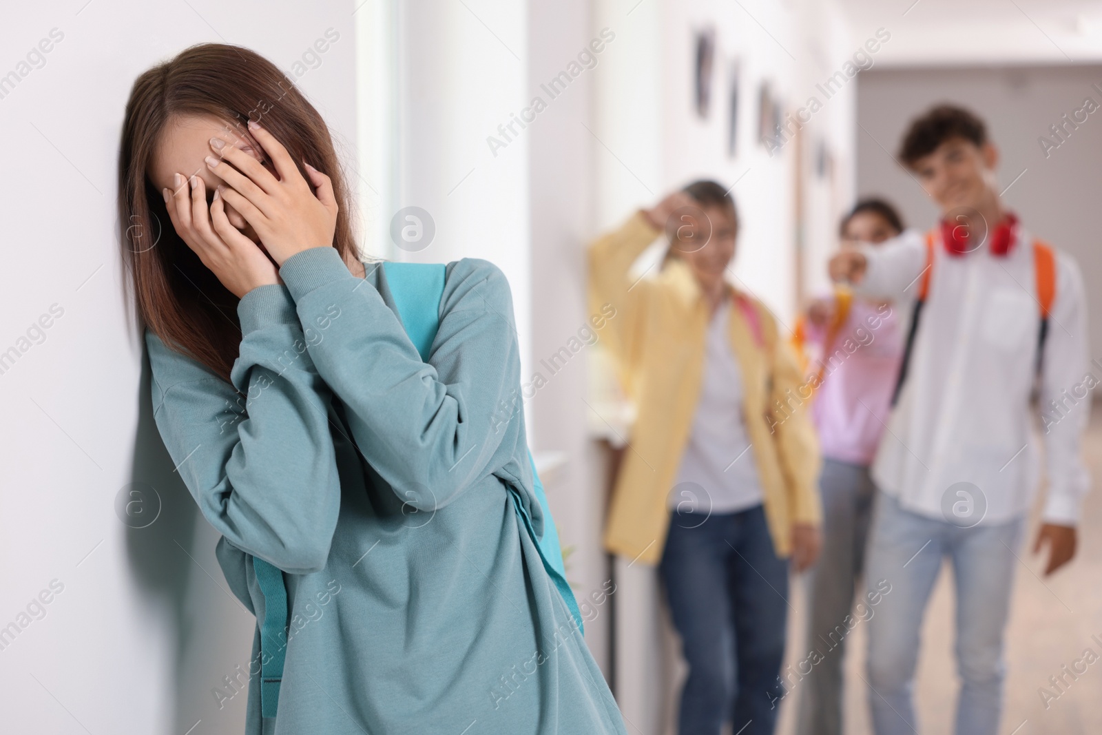 Photo of Teen problems. Lonely girl standing separately from other students at school