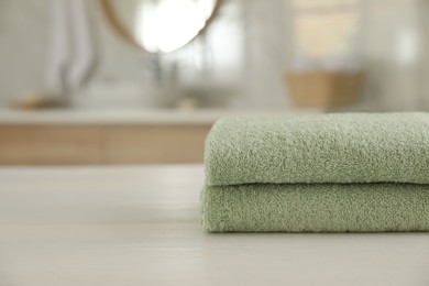 Photo of Stack of clean towels on white wooden table in bathroom. Space for text