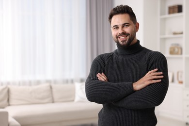 Happy man in stylish sweater at home, space for text