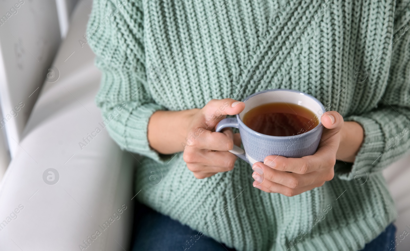 Photo of Woman with cup of hot tea indoors, closeup. Cozy home atmosphere