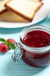 Sweet raspberry jam and toasts for breakfast on turquoise wooden table, closeup