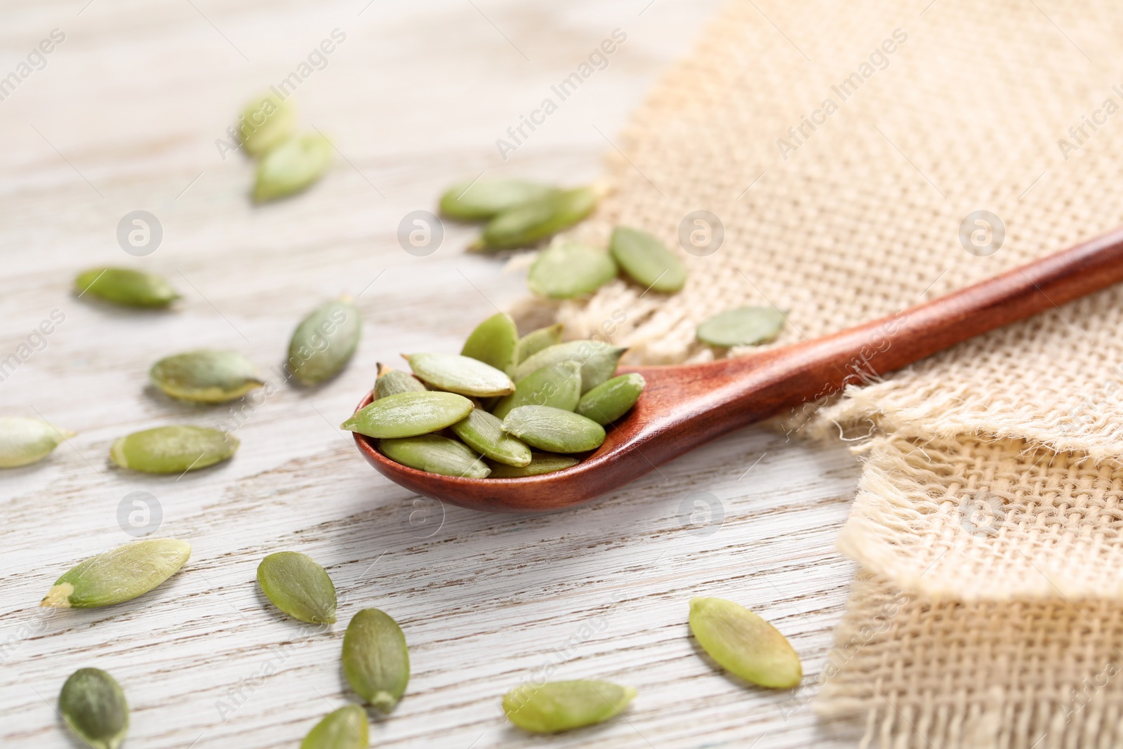 Photo of Spoon with peeled seeds on light wooden table