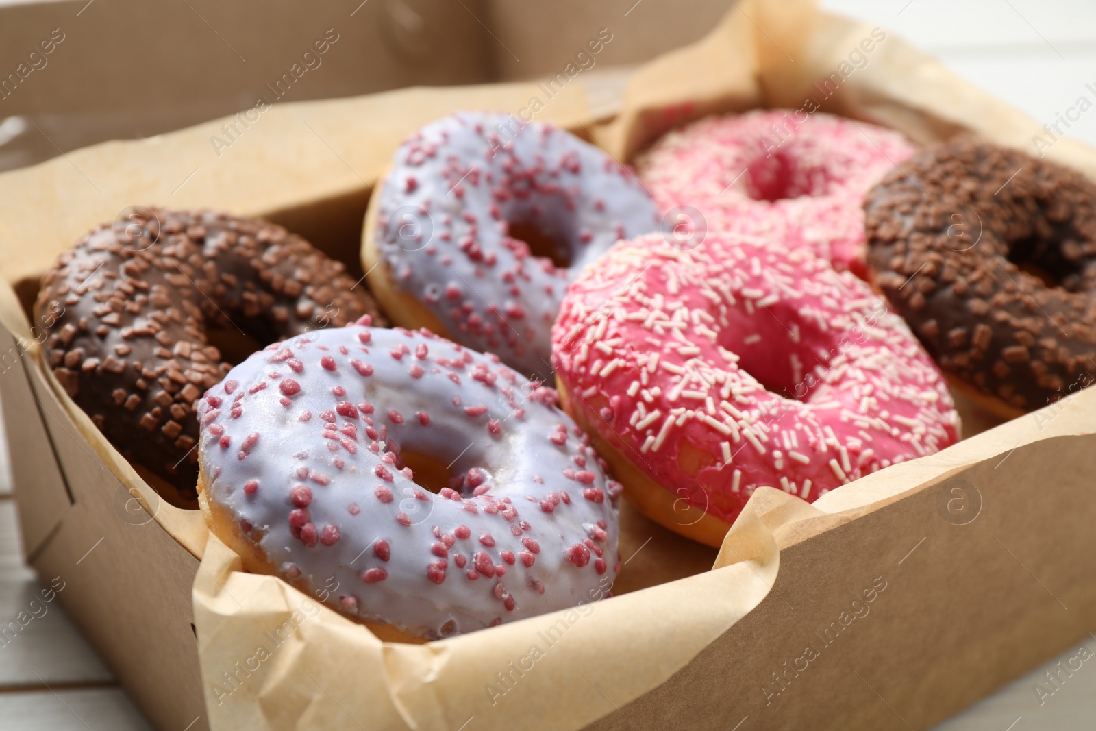 Photo of Sweet delicious glazed donuts in box, closeup