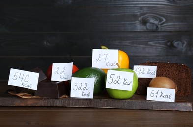 Photo of Food products with calorific value tags on wooden table. Weight loss concept