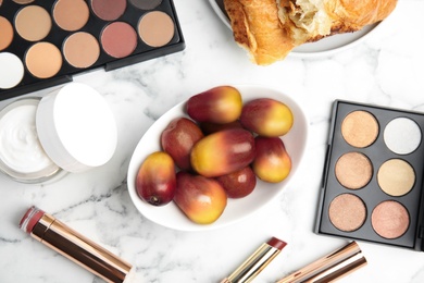 Fresh ripe palm oil fruits, croissant and cosmetic products on white marble table, flat lay